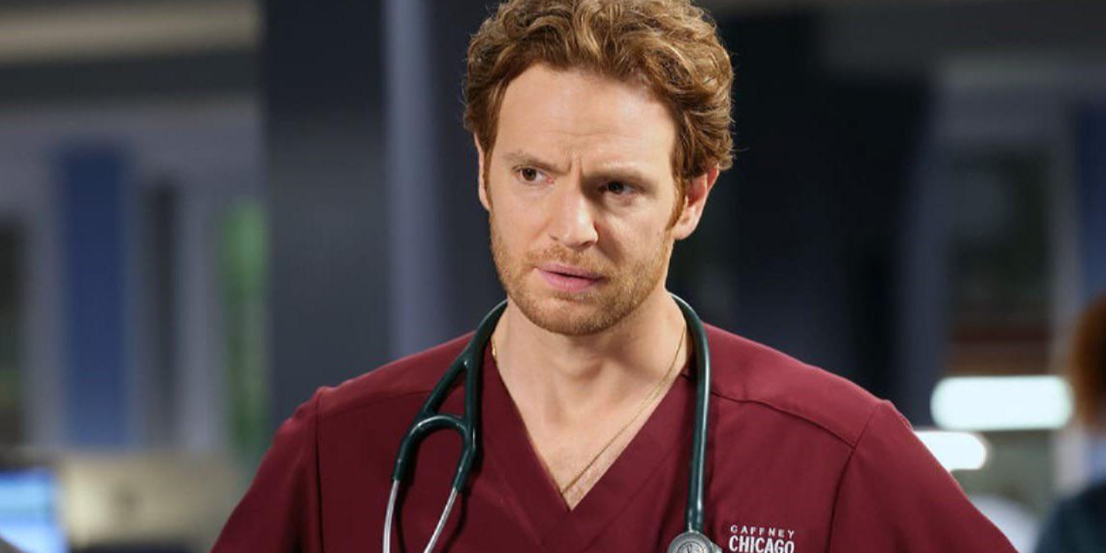 Chicago Med Will Halstead wearing red scrubs and stethoscope around his neck