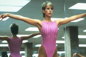 Jamie Lee Curtis with her arms out to the side in an aerobics class in Perfect
