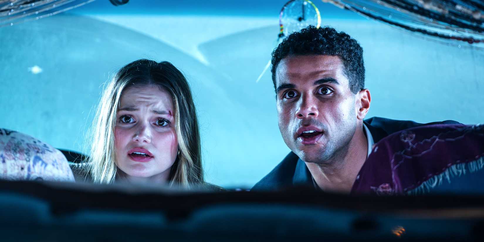 Olivia Holt und Mason Gooding sitzen auf dem Vordersitz eines Lieferwagens und blicken mit herzhaften Augen nach hinten