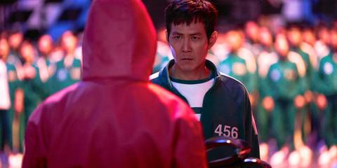 Seong Gi-hun (Lee Jung-jae) in front of one of the guards, about to vote for the game to end in Squid Game Season 2
