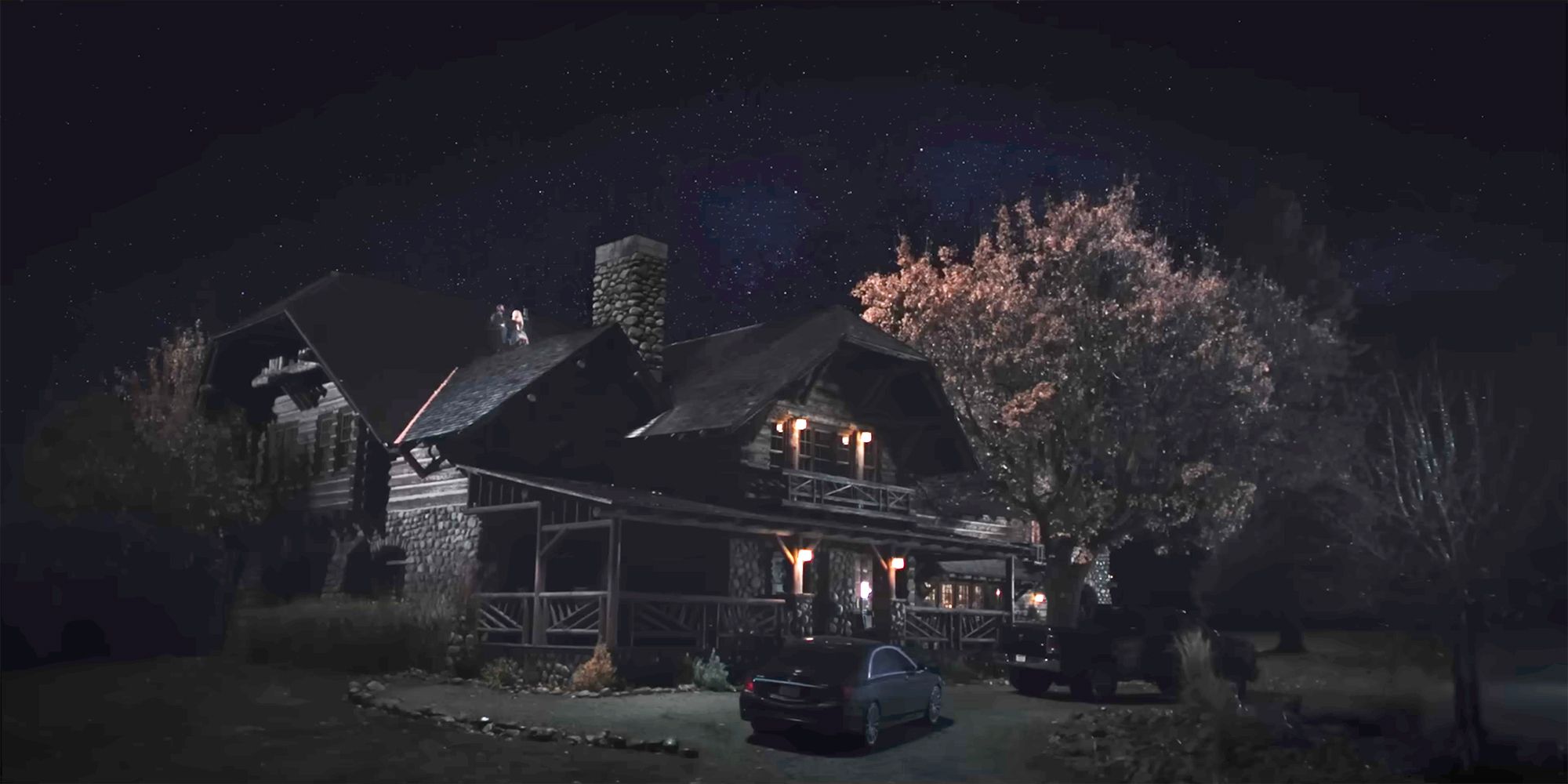 A wide shot of the house in Yellowstone with Beth and Rip on the roof
