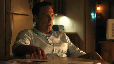 Ben Affleck como Christian tamborileando con la mano sobre la mesa mientras habla con Marybeth de Cynthia Addai-Robinson en The Accountant 2