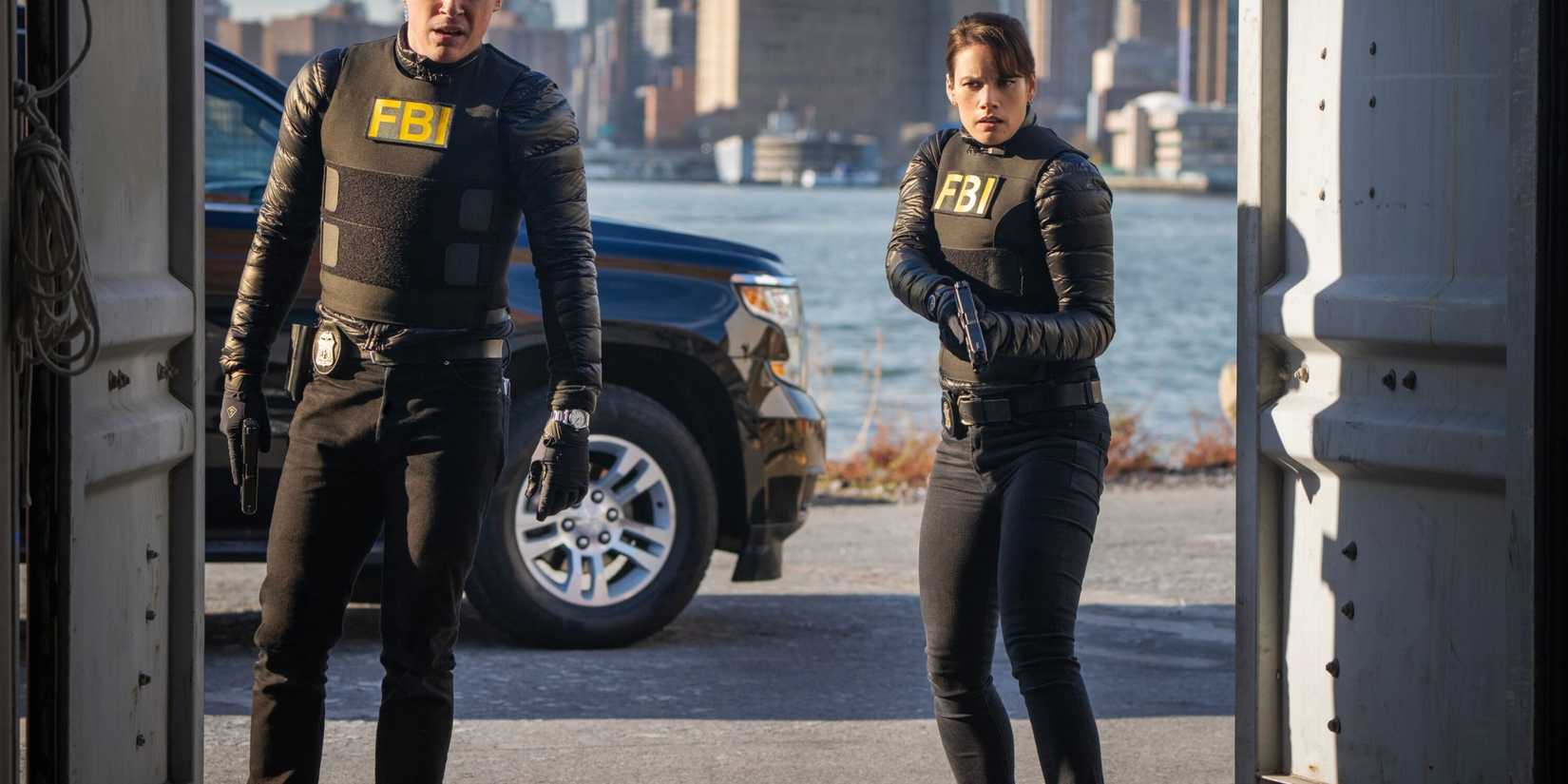 FBI Scola and Maggie standing in the doorway of a warehouse on the water with their guns drawn
