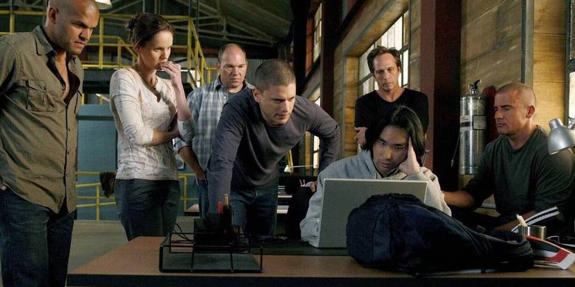 The main cast of Prison Break surrounding a laptop and looking worried
