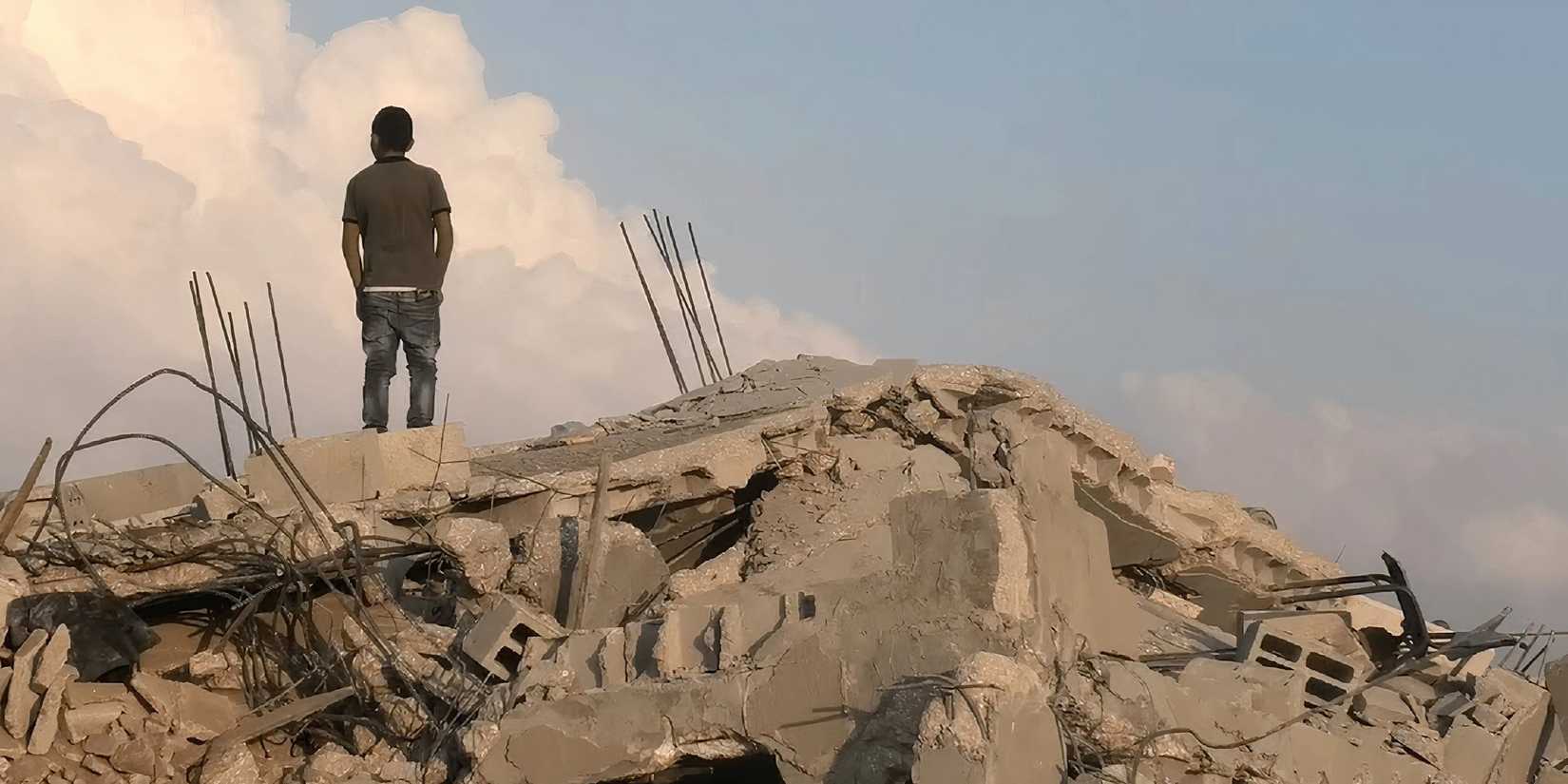 A man standing atop rubble in No Other Land