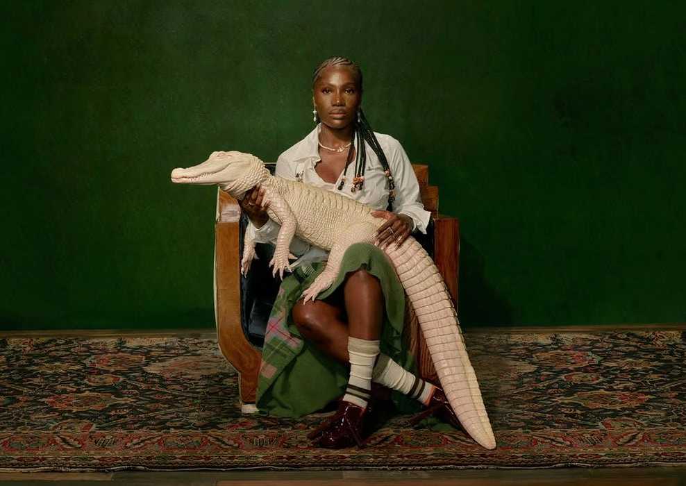 This album cover features a woman holding a white alligator against a green background while sitting in a chair on a carpeted floor. She's wearing a green dress with a white shirt, white socks, and dark shoes.