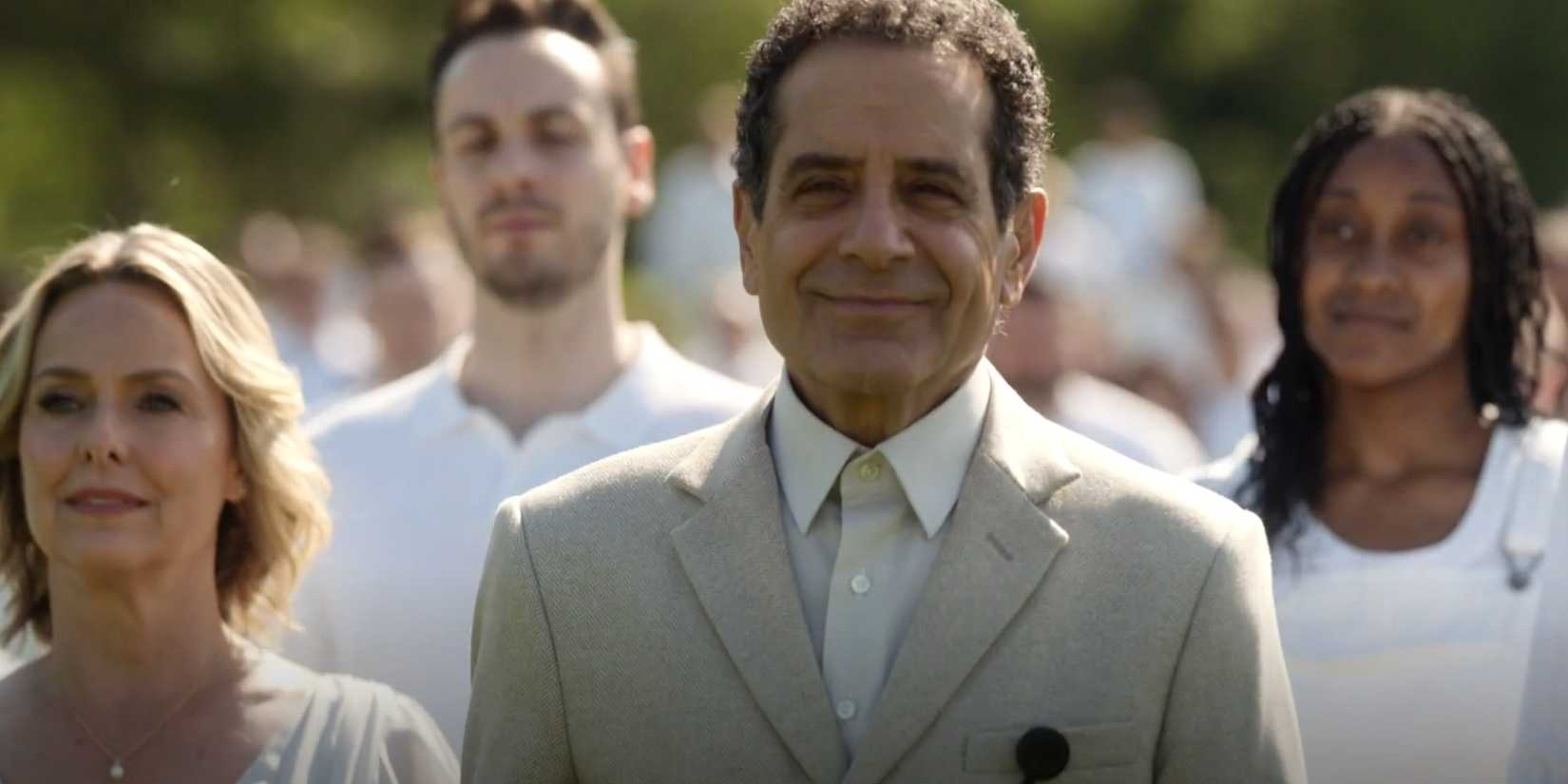 Adrian Monk (Tony Shalhoub) smiling while walking with a crowd dressed in white in Mr. Monk's Last Case: A Monk Movie
