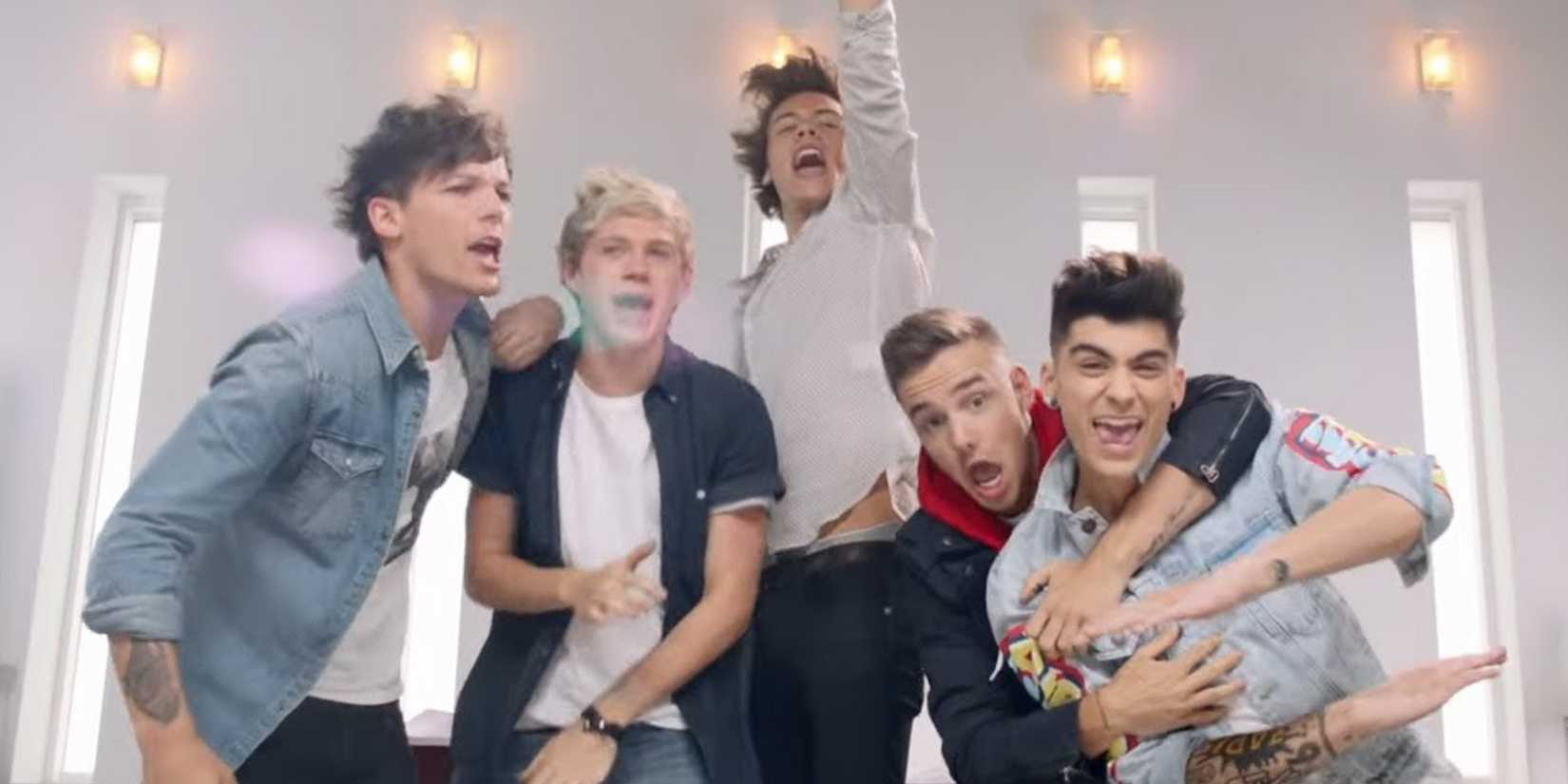 The background is white with several small windows. There are five members in the photo, two are in denim jackets, one is in a white shirt, one is in a dark blue jacket, and a white shirt and a blue button that is open.