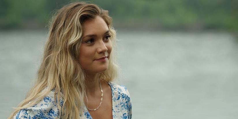 Lola smirks while standing near the lake in Sullivan's Crossing