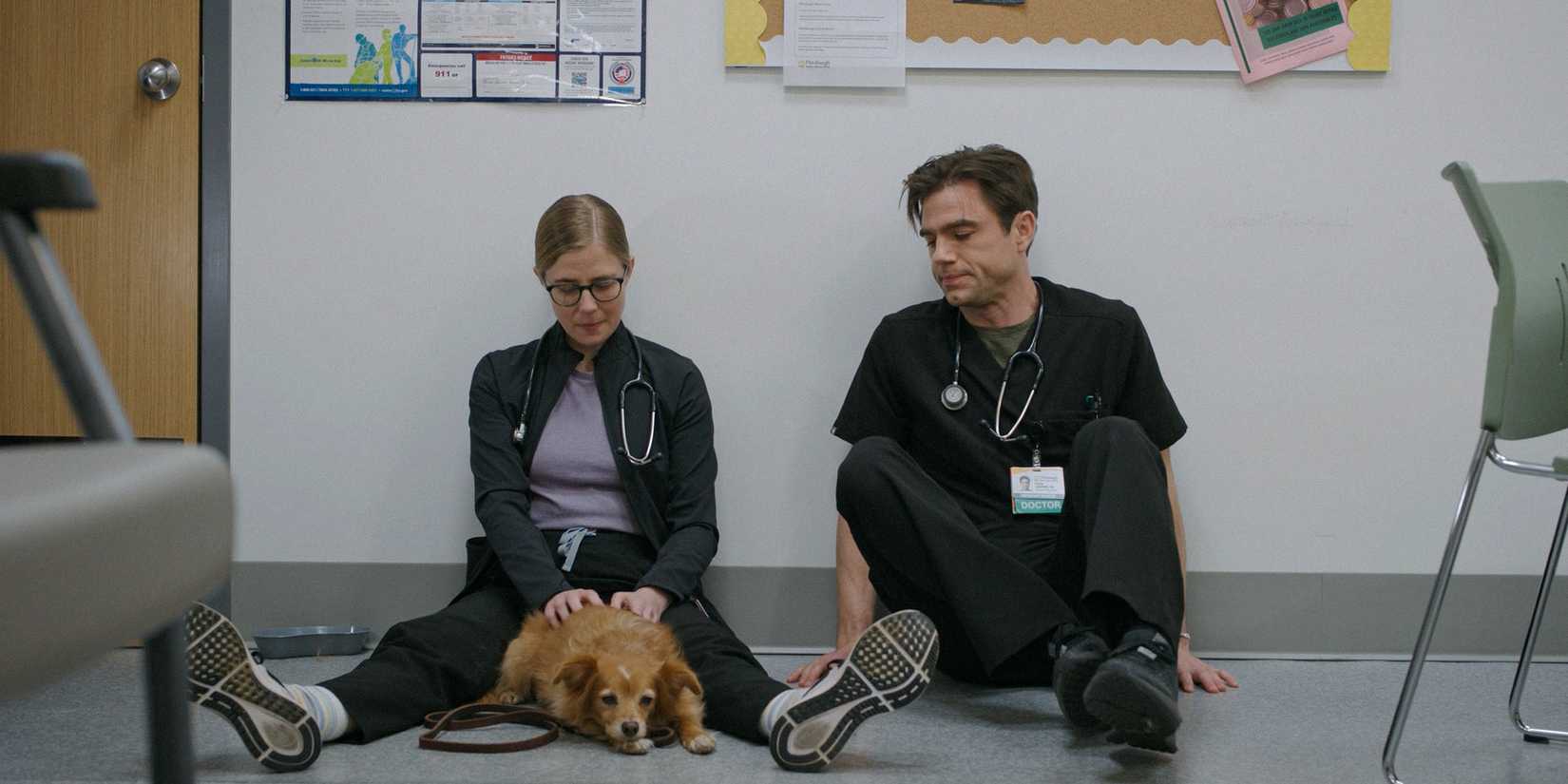 Dr. Melissa King (Taylor Dearden) and Dr. Frank Langdon (Patrick Ball) take a break while petting a dog on The Pit Season 1 Ep 9