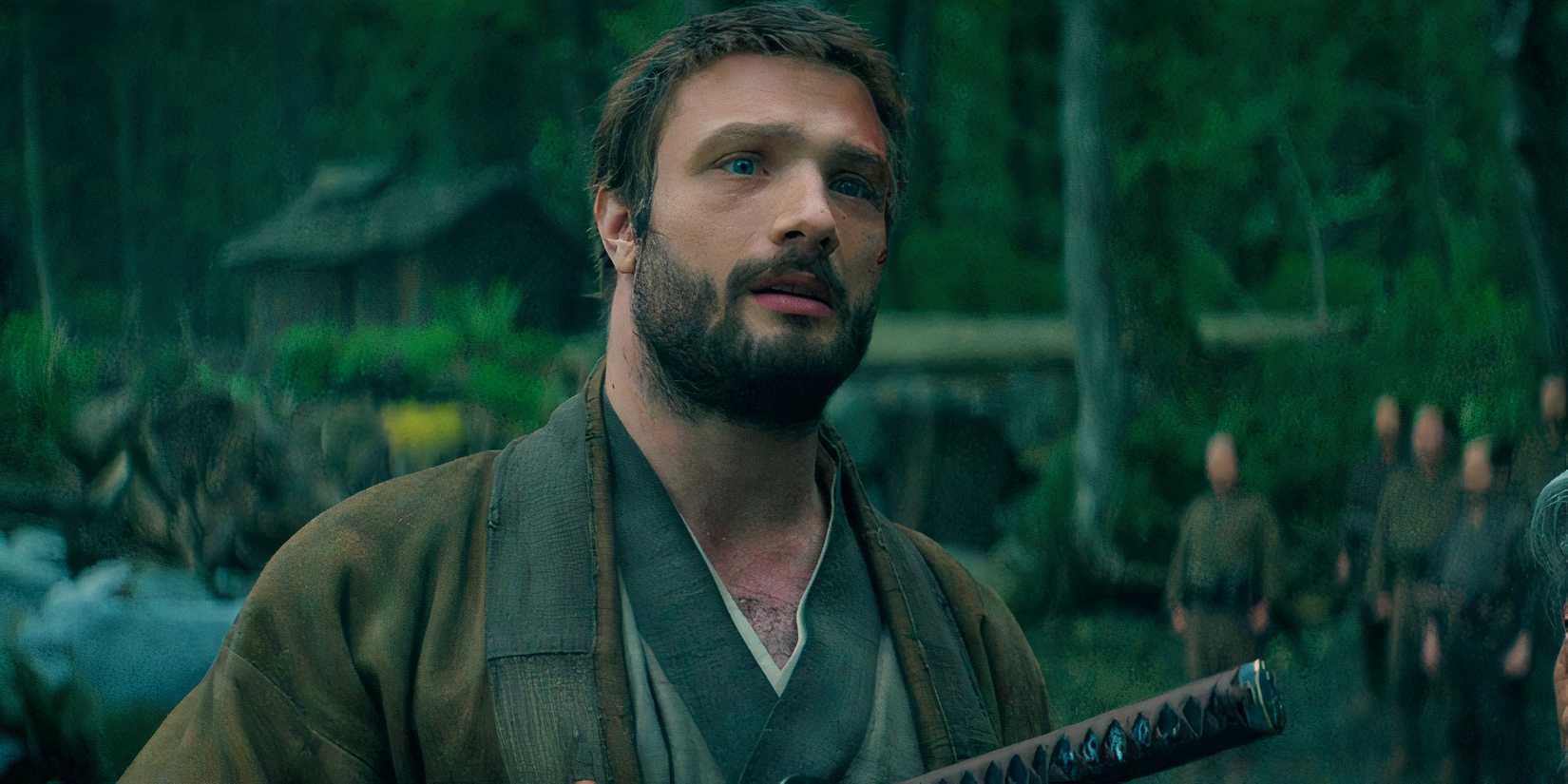 Cosmo Jarvis as John Blackthorne stands on a beach with a sword in Shogun season 1