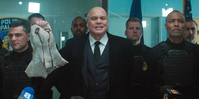 Wilson Fisk (Vincent D'Onofrio) e a Força-Tarefa Anti-Vigilantes apresentando a máscara de Muse à imprensa em Daredevil: Born Again Temporada 1 Episódio 7