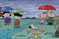 The Peanuts gang in the rain with umbrellas.