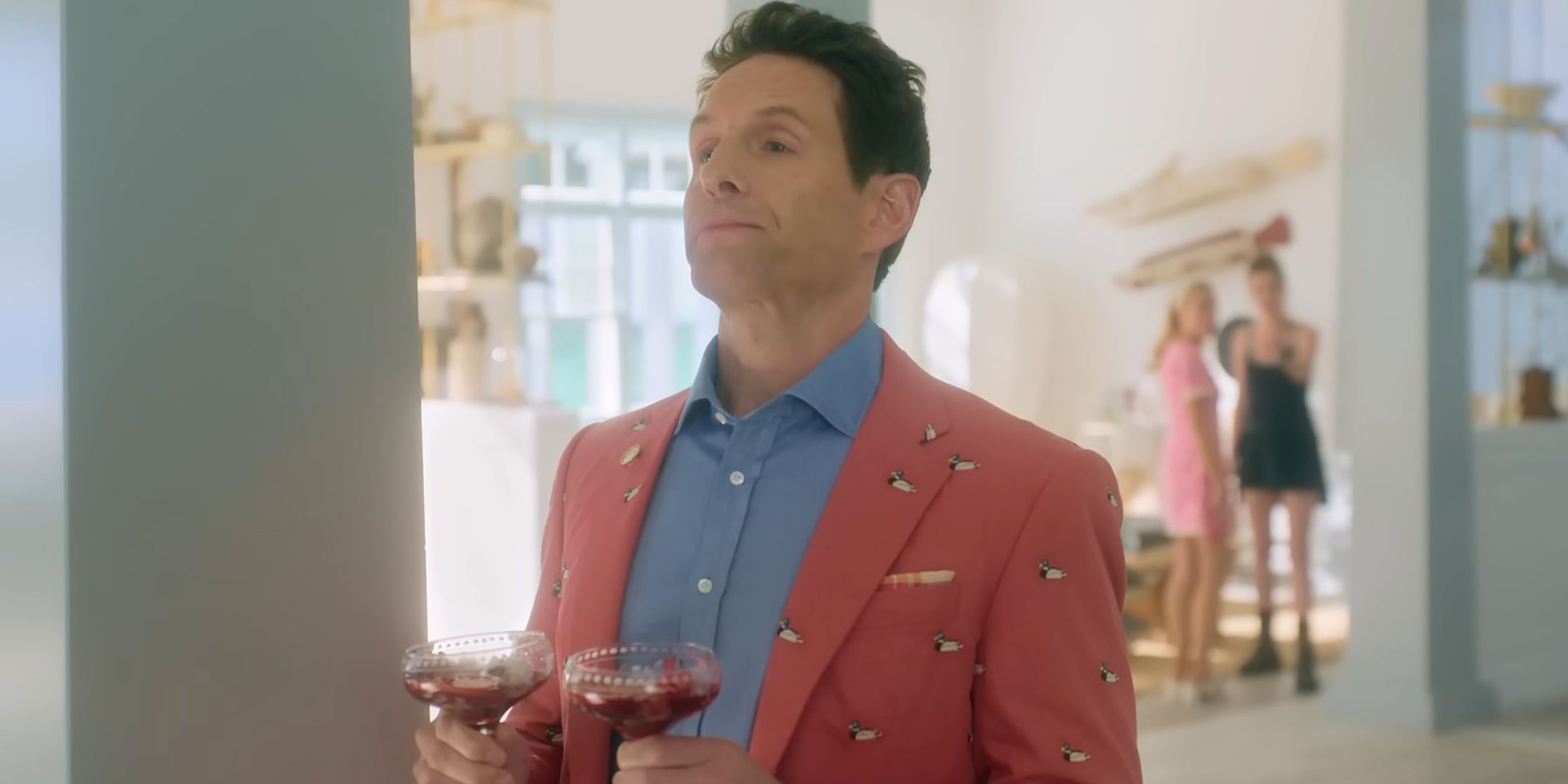 Glenn Howerton as Ethan looking smug while holding two glasses in Sirens