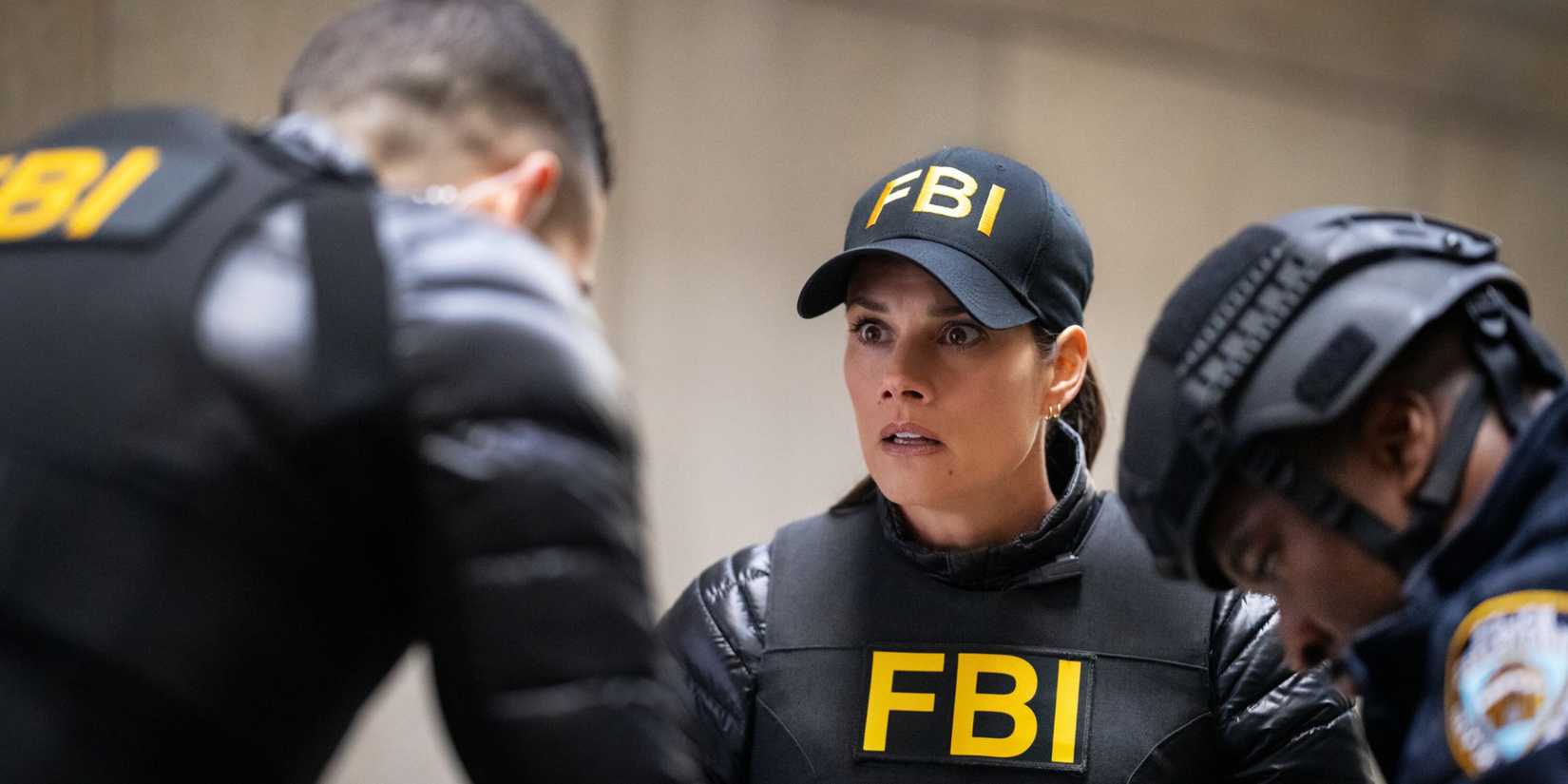 Maggie in her FBI jacket and hat with a shocked expression on her face while OA bends over her