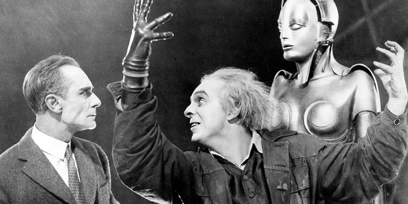 Um cientista gesticula amplamente na frente de seu robô enquanto outro homem olha em Metropolis