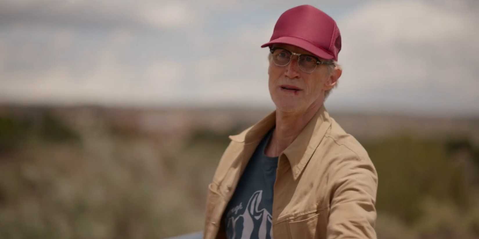Dr. Reynolds (Christopher Heyerdahl) wearing a red hat on a moving train in Dark Winds season 3, episode 8