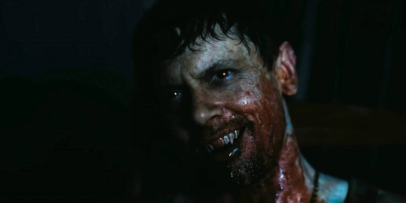 Remmick (Jack O'Connell) with a bloodstained face and a sinister smile in Sinners