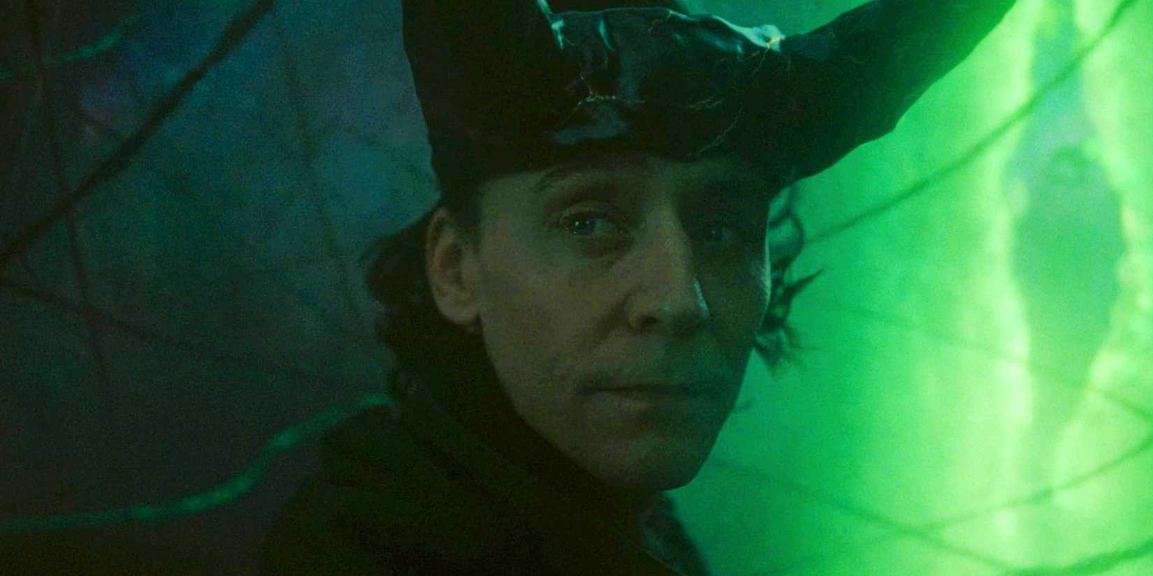 Tom Hiddleston As Loki Looking Over His Shoulder With A Green Multiverse Rift In The Background In The Loki Season 2 Finale