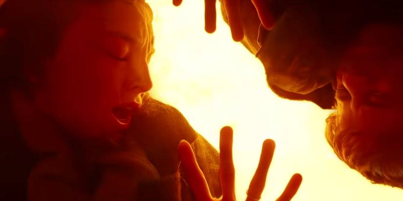 Two people pressed against a surface with bright fire behind them in 28 Years Later