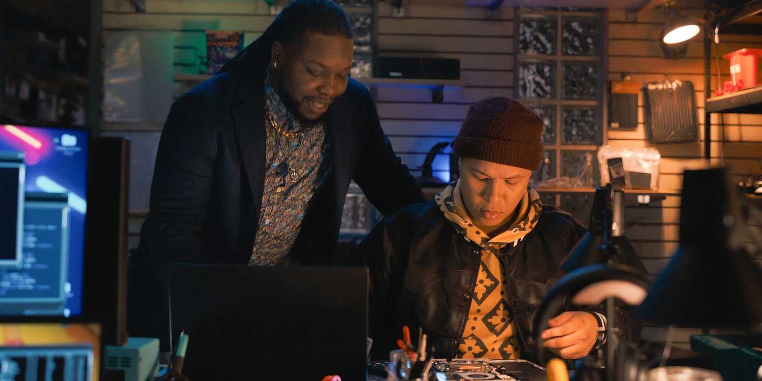 Randy standing at Bobby's shoulder at the computer desk