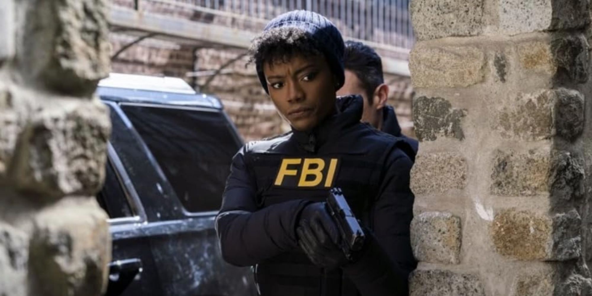 Katherine Renee Kane as Tiffany in FBI, wearing black hat and FBI gear and pointing a gun around a corner