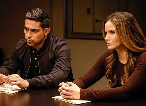 Wilmer Valderrama's Nick Torres and Katrina Law's Jessica Knight sitting at an interrogation table in NCIS
