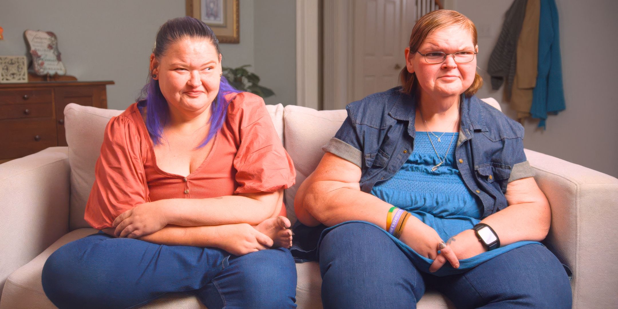 1000-lb Sisters' Tammy and Amy Slaton close up sitting on a couch smirking