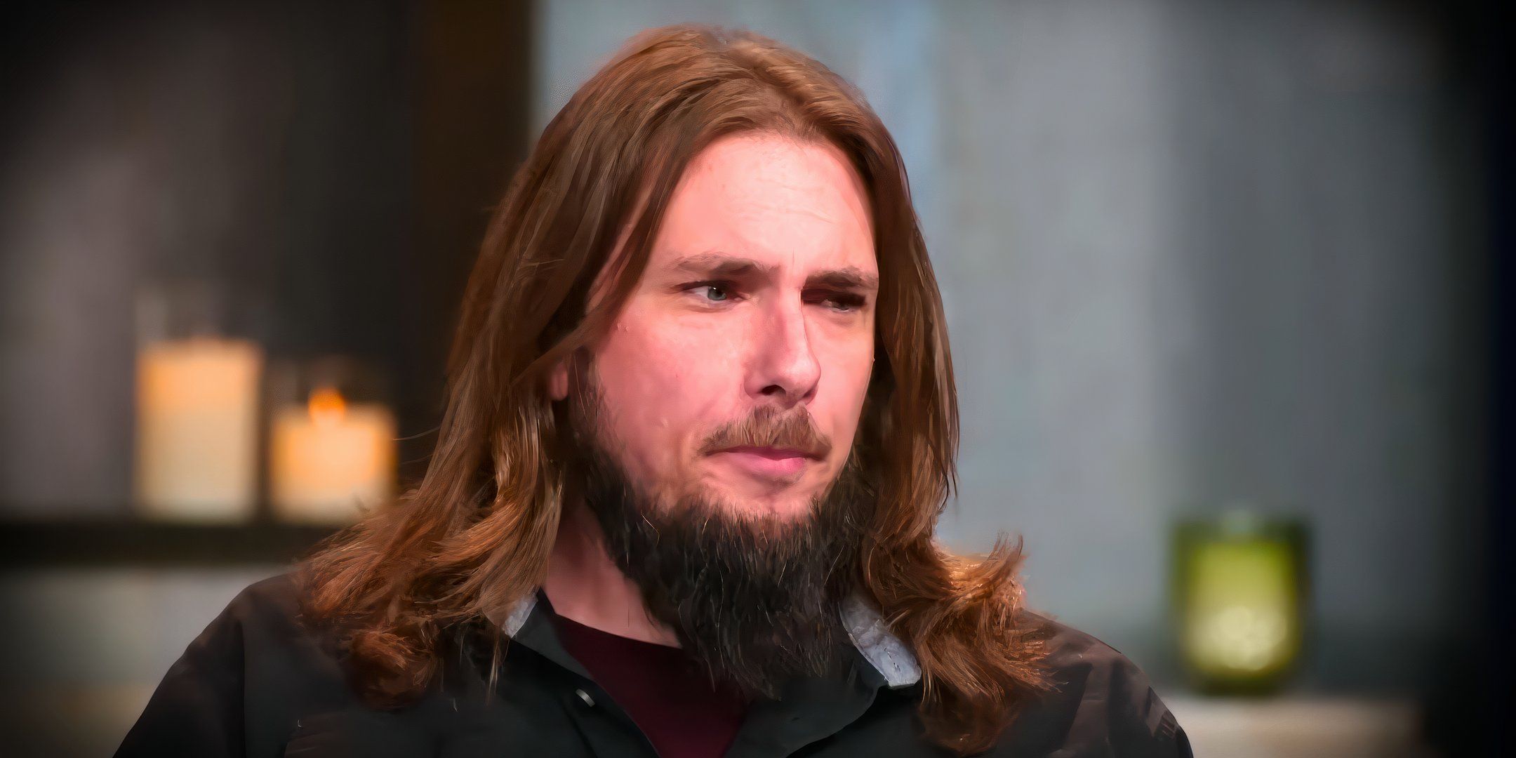 90 Day Fiancé Colt Johnson with long hair and back shirt looking suspicious