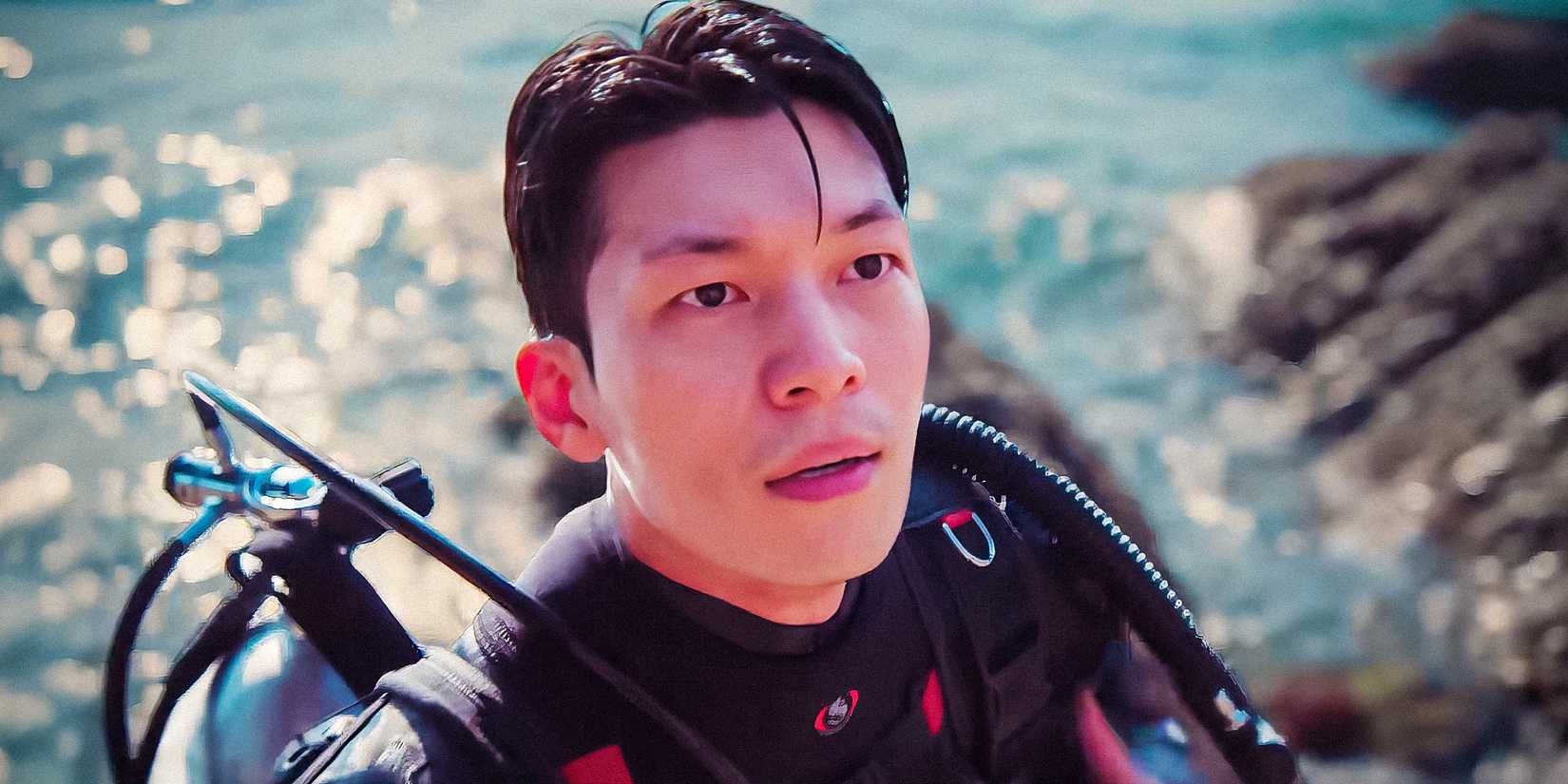 Wi Ha-joon as Jun-ho emerging from the water wearing scuba diving gear while looking upwards in Squid Game