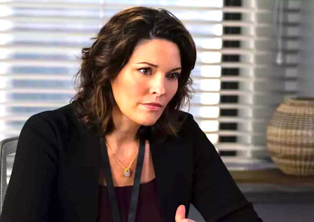 Alana de la Garza's Isobel sits at a desk frowning in FBI season 7