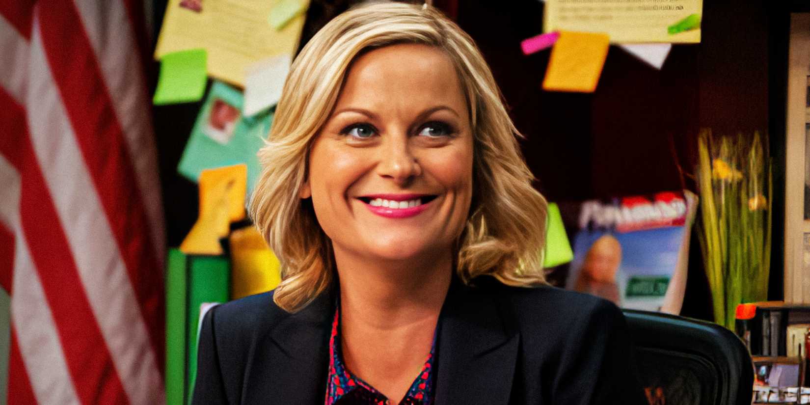 Amy Poehler smiling as Leslie Knope while sitting in her office in Parks and Recreation.