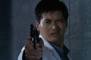 Chow Yun-Fat closes one eye and points a gun.