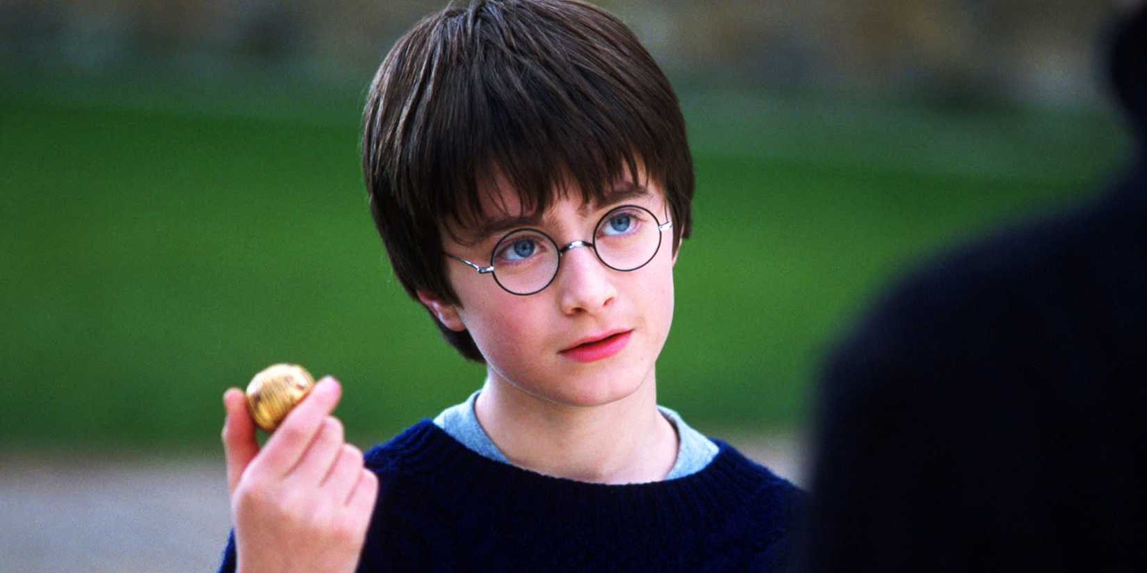 daniel radcliffe as harry potter holding a snitch in sorcerer s stone