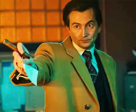 Дэвид Теннант, протягивающий руку, держащий сигару и бумагу, в роли Тони, лорда Бэддингхэма в сериале Rivals.