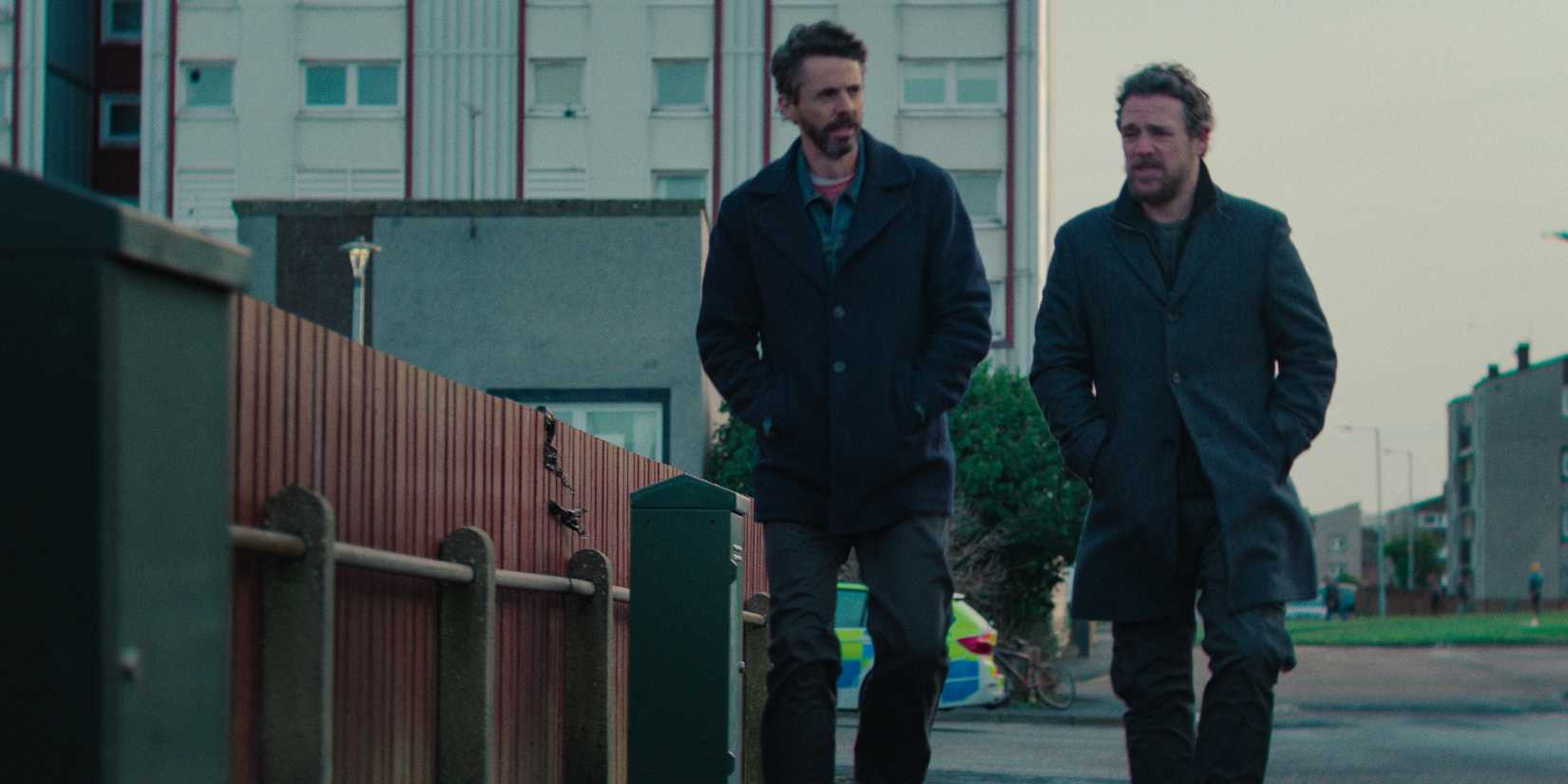 DCI Carl Morck (Matthew Goode) and DI Hardy (Jamie Sives) walking on the street in Dept. Q Season 1