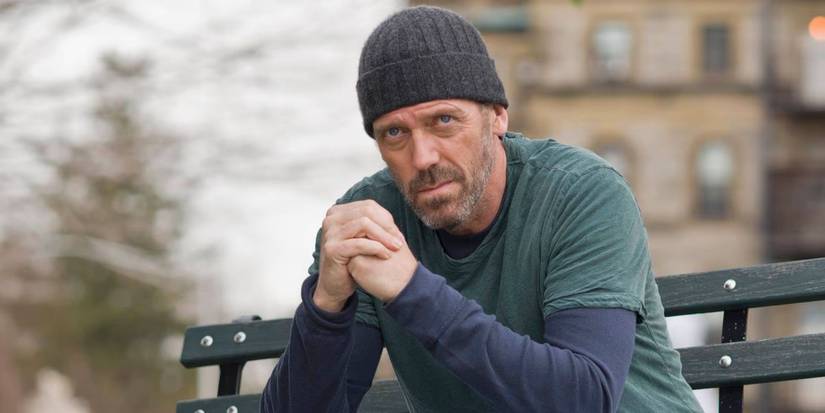Hugh Laurie como Dr. Gregory House sentado em um banco com as mãos cruzadas em Broken.
