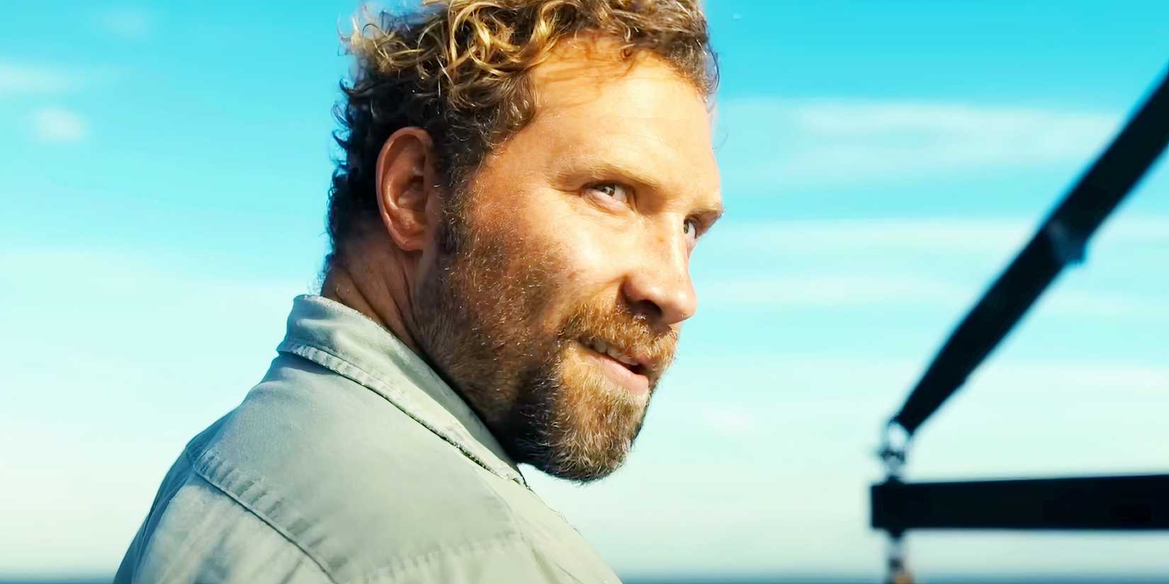 Jai Courtney blickt über seine Schulter mit einem teuflischen Grinsen in Gefährlichen Tiere