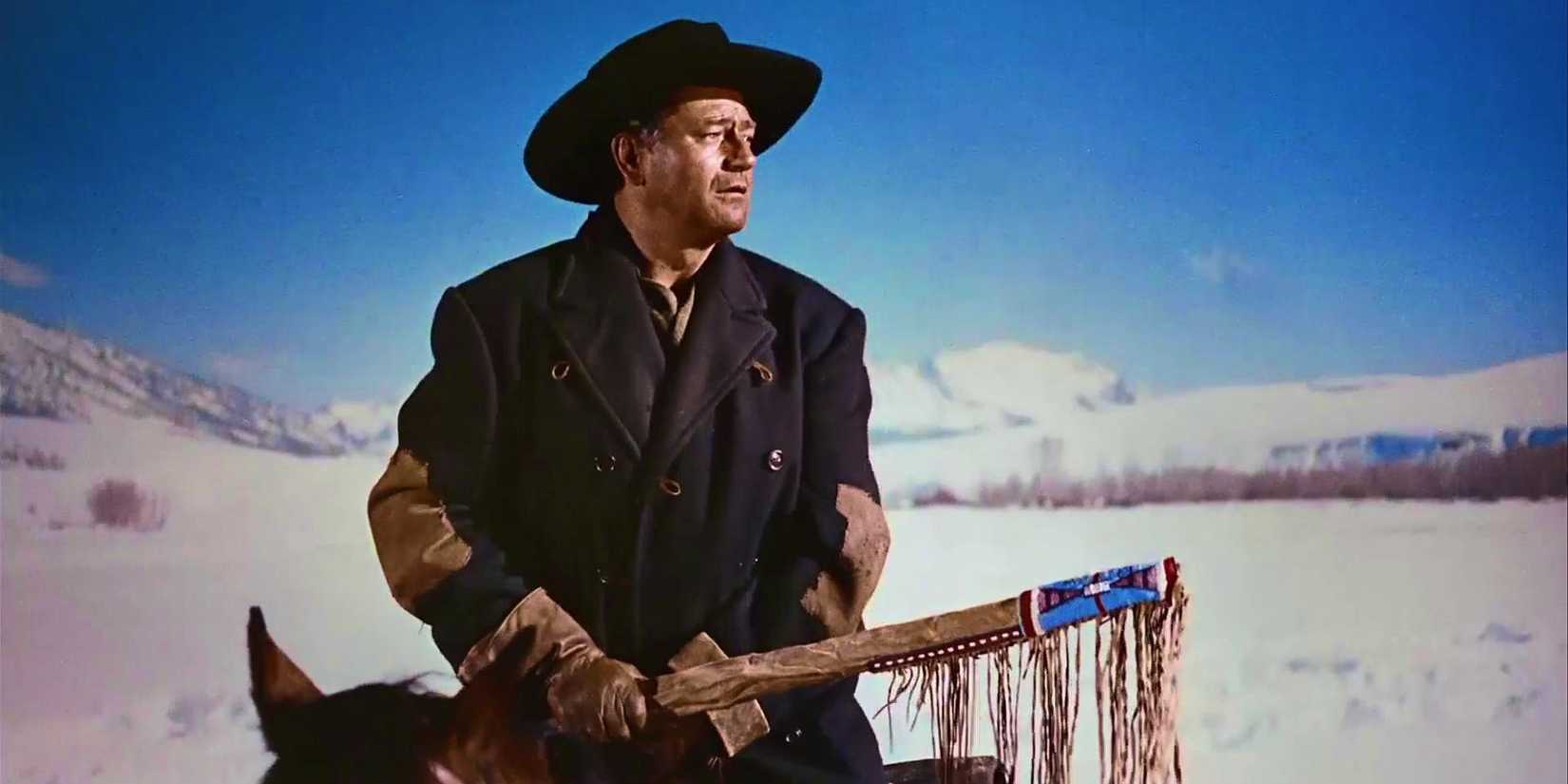 John Wayne as Ethan holding his covered rifle in The Searchers