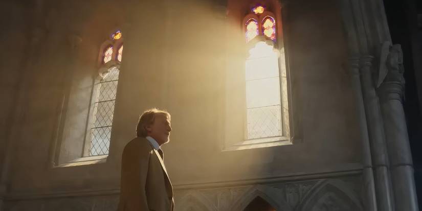 Daniel Craig walking in a church as Benoit Blanc as light shines on him through a window in Wake Up Dead Man A Knives Out Mystery