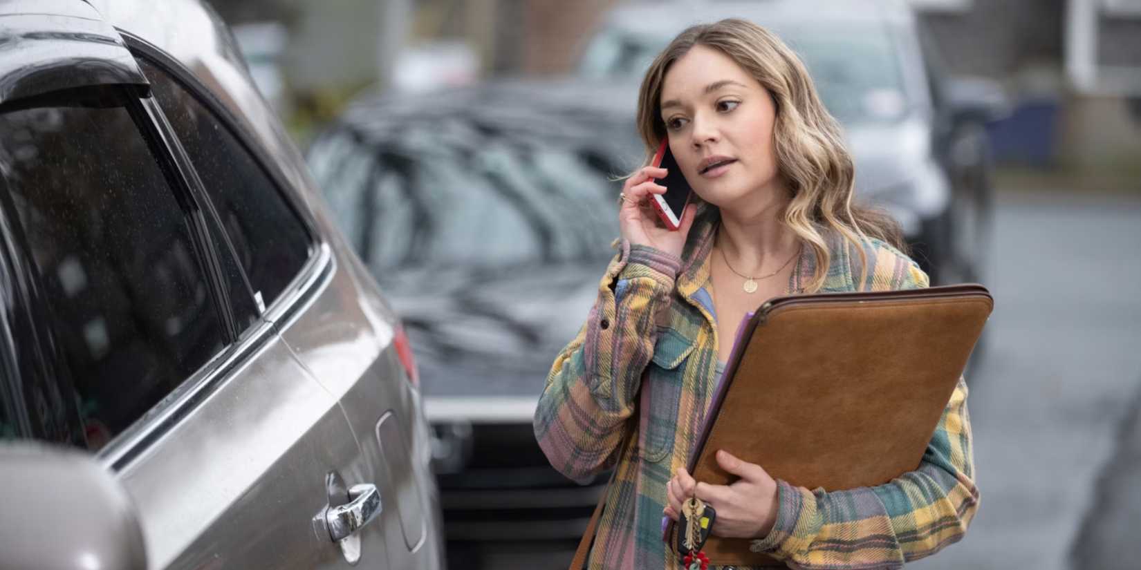 Lola on her phone and holding a large file in Sullivan's Crossing