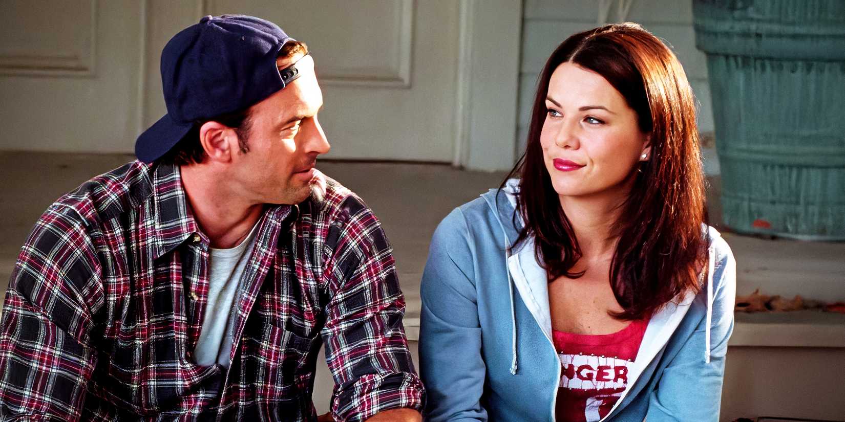 Luke e Lorelai se olhando e sorrindo enquanto sentados nos degraus da frente de uma casa em Gilmore Girls.