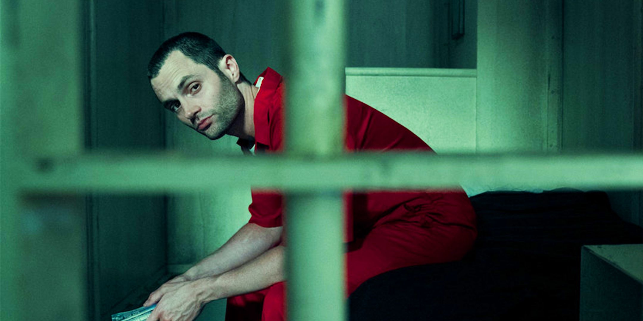Penn Badgley as Joe Goldberg sitting behind bars in prison in You Season 5