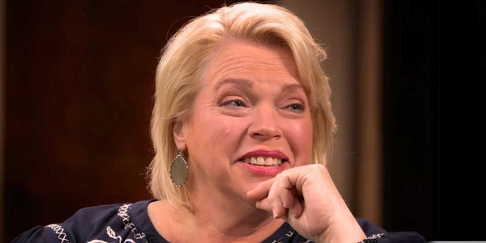 sister wives star janelle brown in a thinking pose with gold earrings and smiling