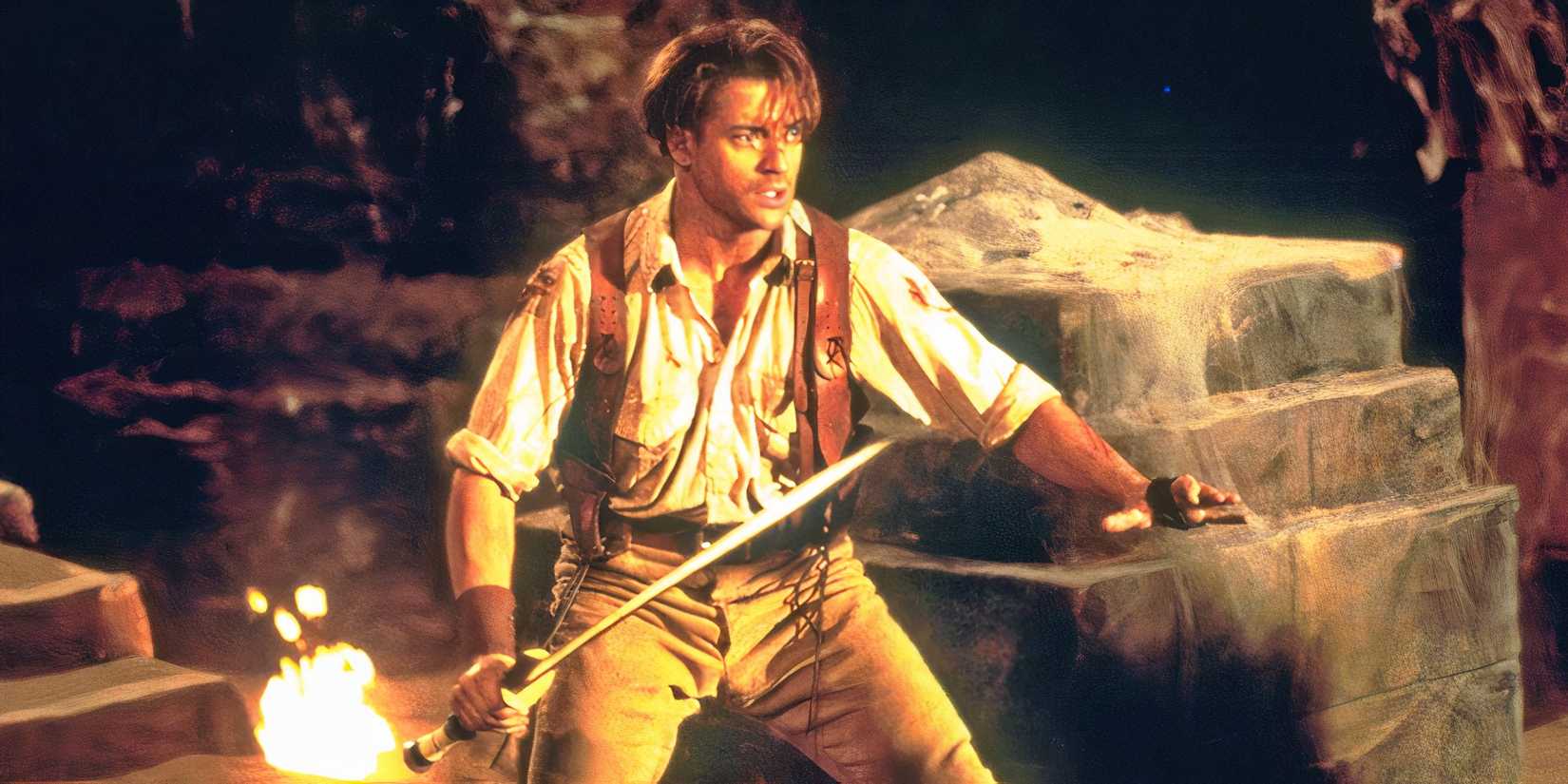 Brendan Fraser holds a sword while standing in a tomb in The Mummy