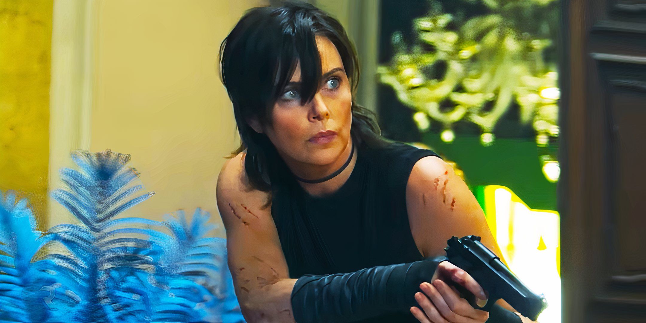 Charlize Theron holding a gun while watching in Old Guard 2