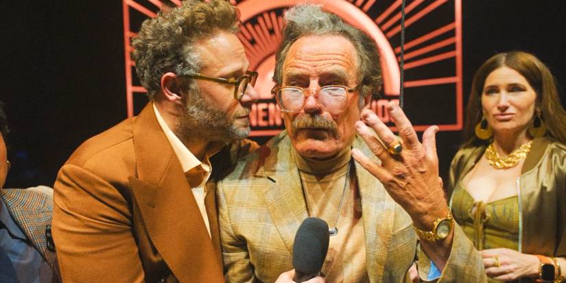 Matt (Seth Rogen) whispering in Griffin Mill's (Bryan Cranston) ear during the  CinemaCon presentation in The Studio Season 1 Episode 10