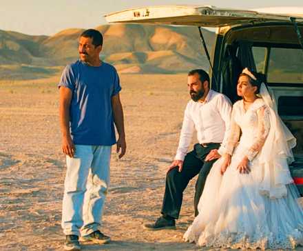 Два мужчины и женщина в свадебном платье сидят рядом с фургоном в пустыне в фильме "It Was Just An Accident"