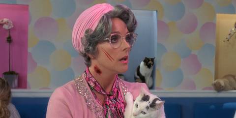 Jane Krakowski as Jenna Maroney wearing pink and holding a cat, with a scratch on her face, in 30 Rock's pilot.