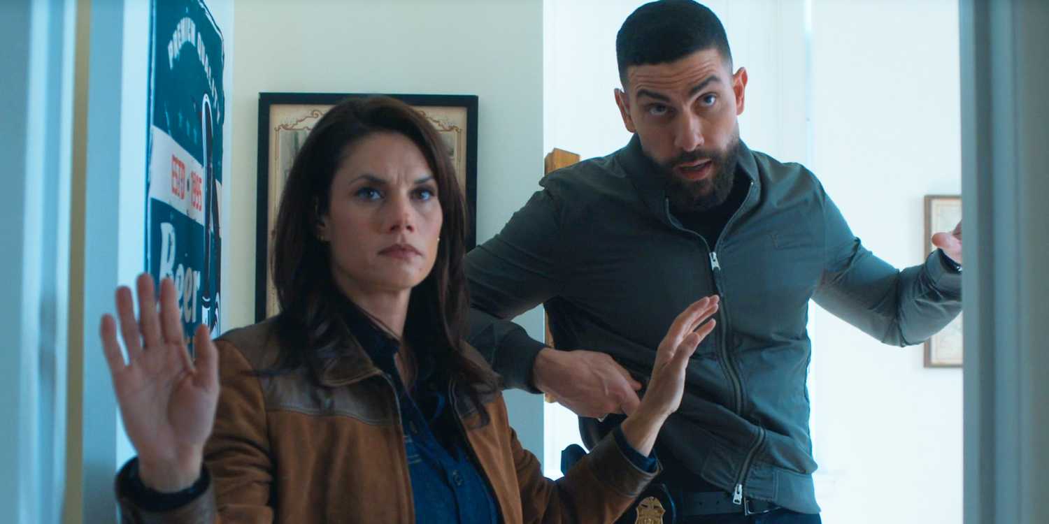 Maggie and OA standing in a doorway with their hands up in FBI